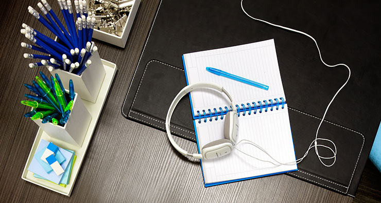 organized desktop with paper, pens, headphones