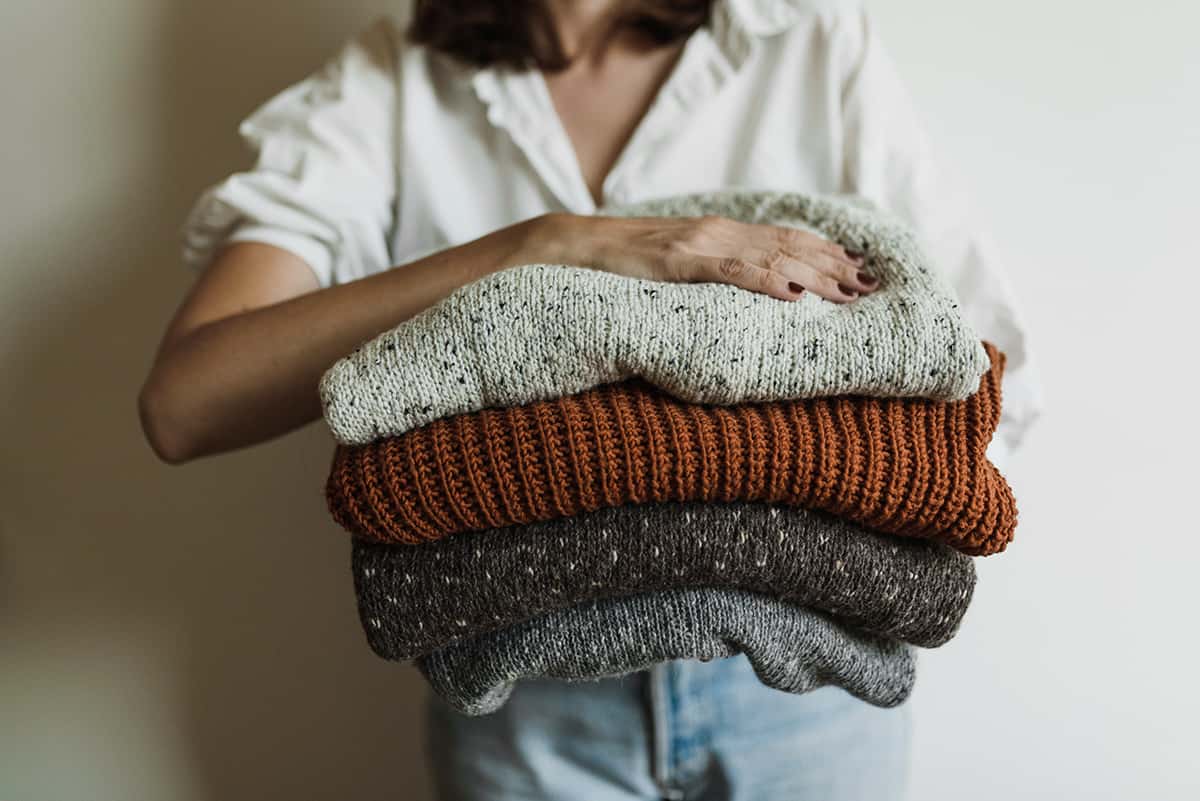 woman holding folded sweaters