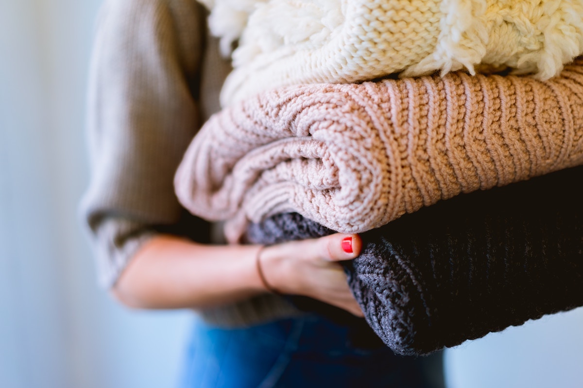 Woman holding sweaters, seasonal clothes storage