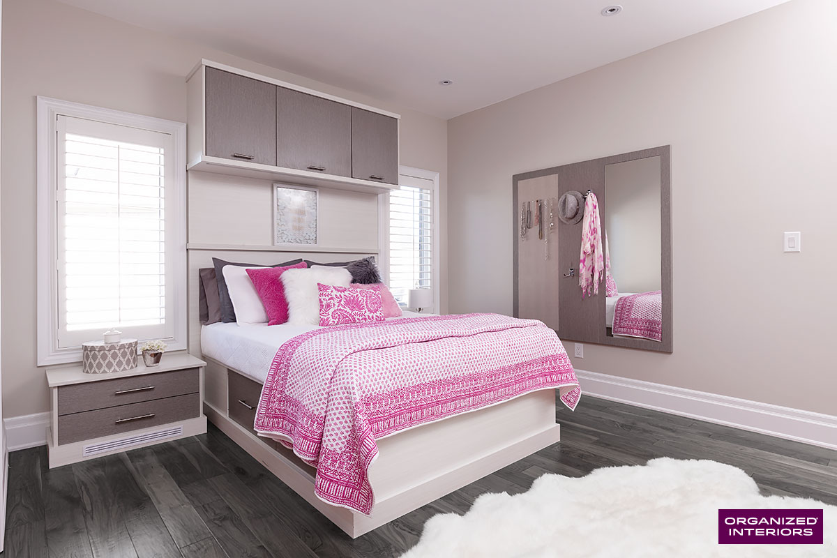 bed with pink comforter built-in bedroom cabinetry for winter clothes storage