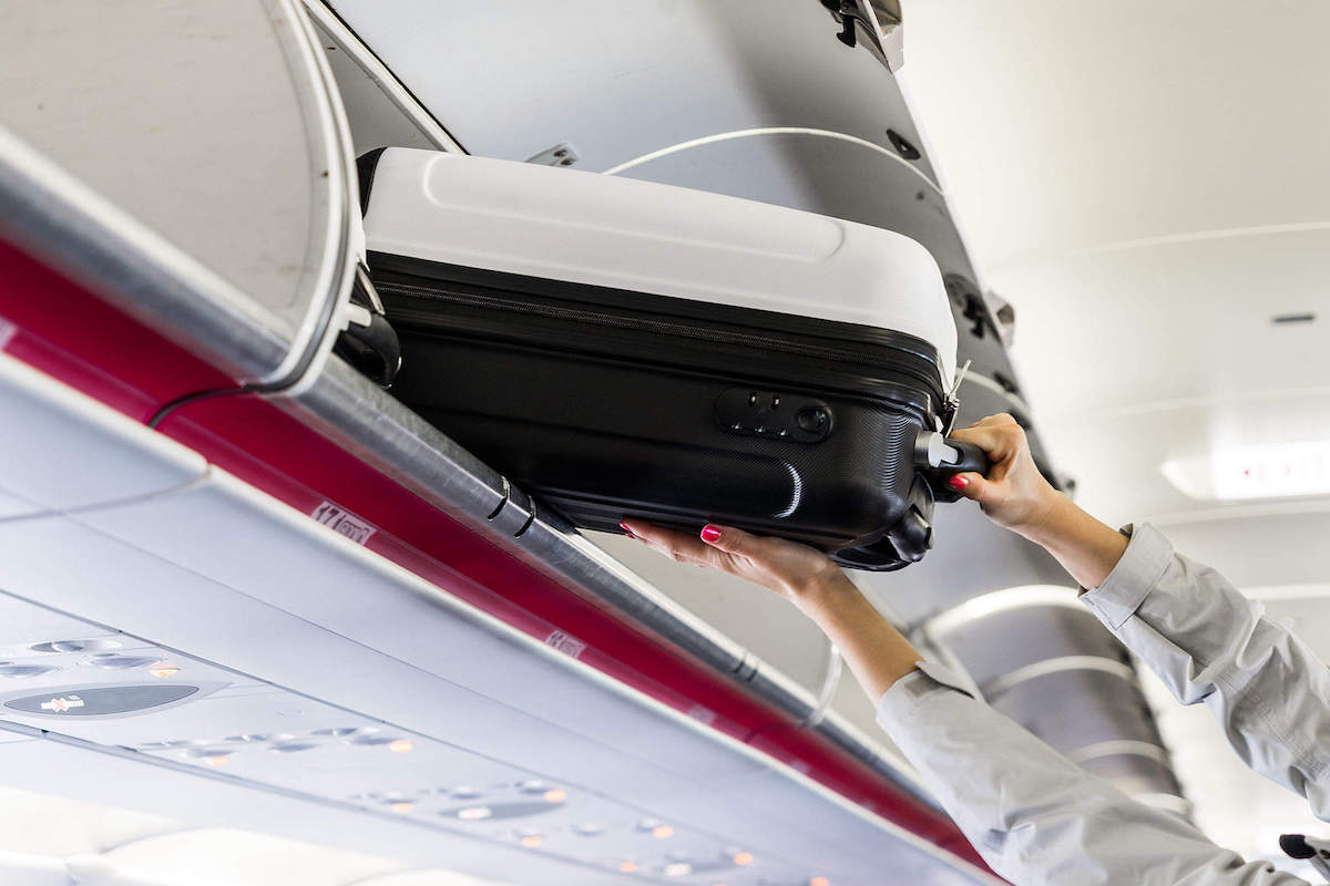 woman on plane getting luggage, post-vacation fatigue