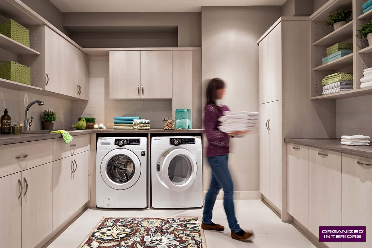  woman carrying linens past washer and dryer