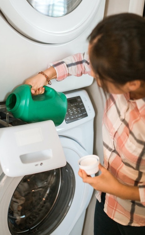 woman pouring laundry detergent into washer