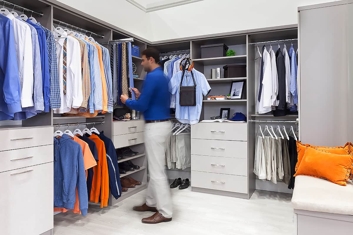 man choosing tie in walk-in closet