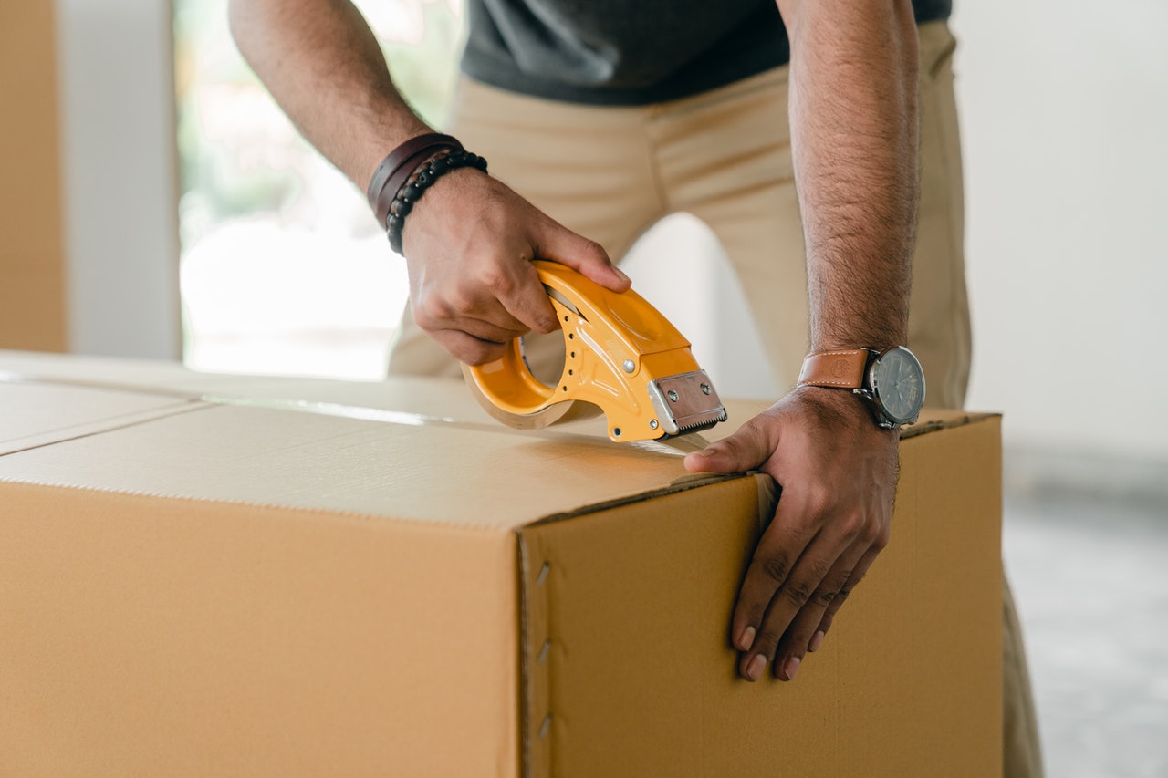 man taping storage box