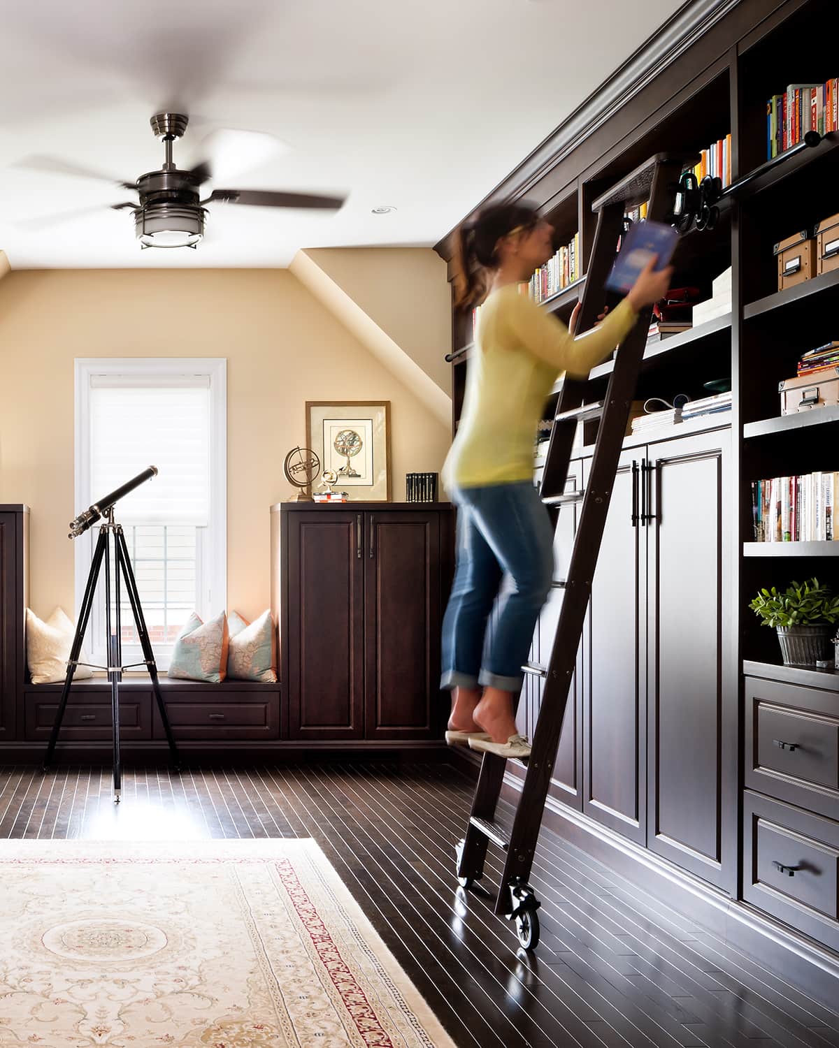 woman on ladder grabbing book off custom bookcase