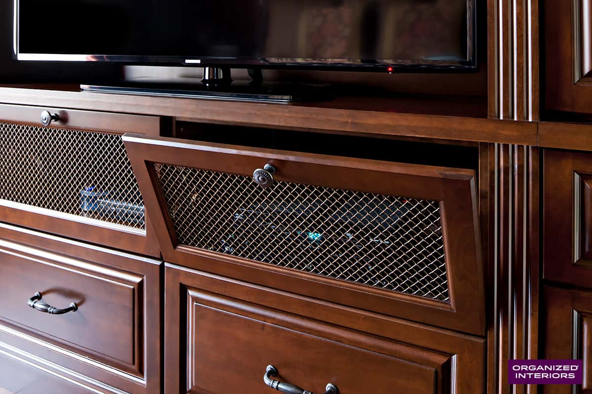 built-in cabinet with cable box behind a metal grill door