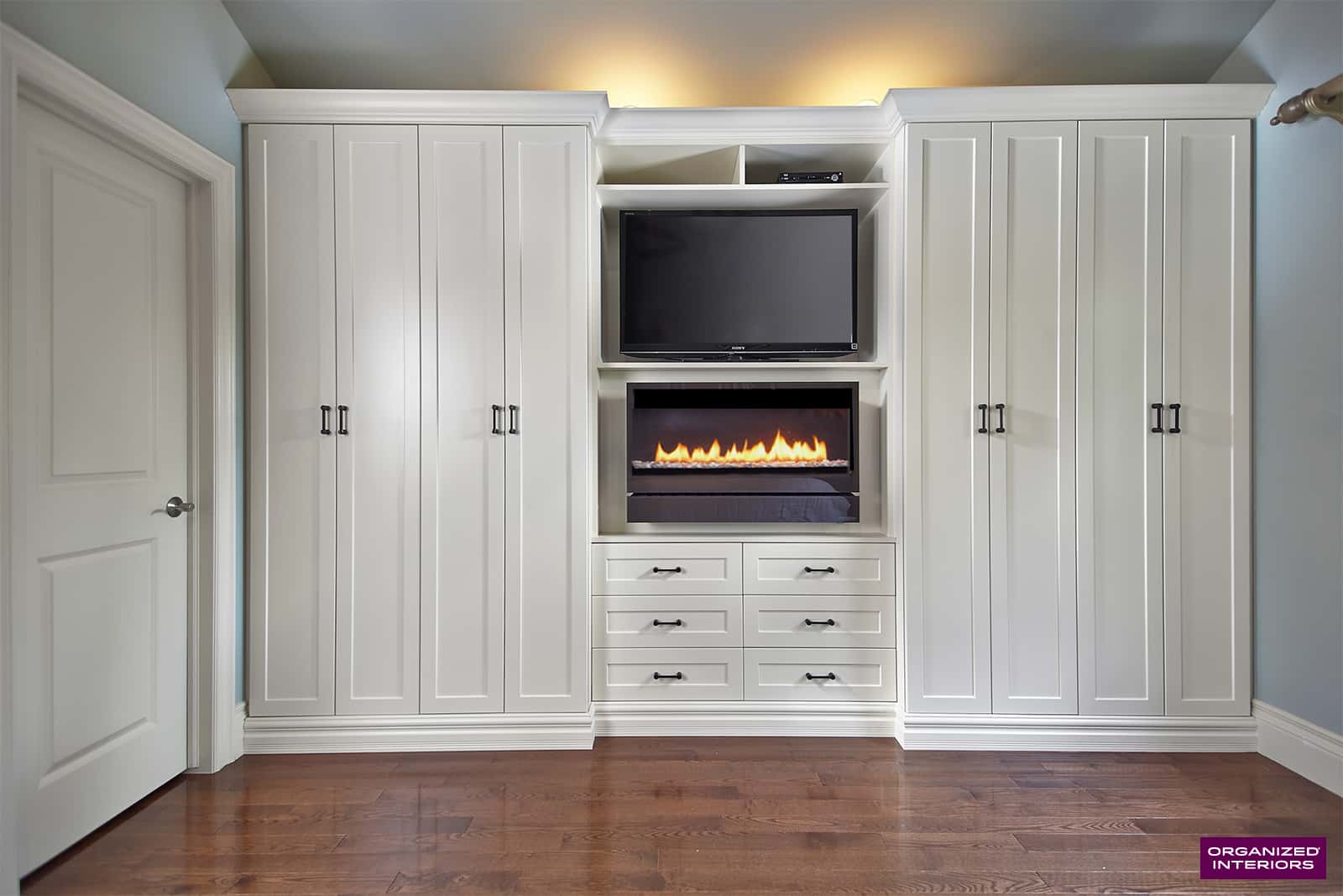 white wardrobe closet with fireplace, TV, and custom built-ins for a master bedroom